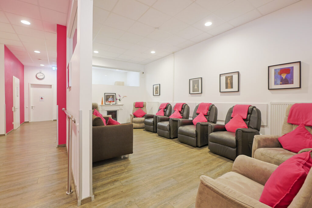 Heller Aufenthaltsraum mit bequemen Ruhesesseln, klaren Wegen und Handläufen in der Tagespflege am Kanal.