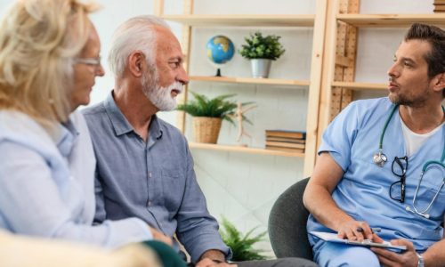 Pflegefachkraft im Gespräch mit Senior und Angehöriger zu Hause – Erstbesuch, Bedarfsklärung, Pflegeplanung.